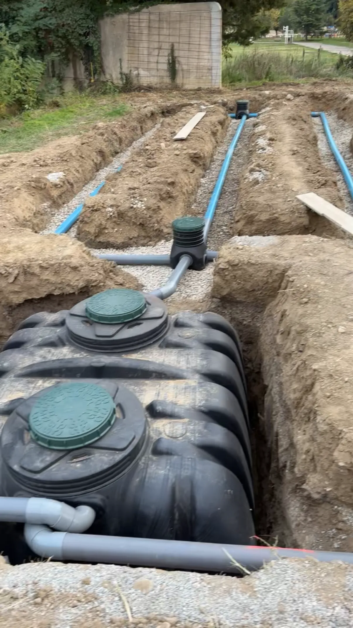 Photo de chantier : préparation de fondation pour une piscine, cuve posée et tranchées gravillonnées en attente de remblai